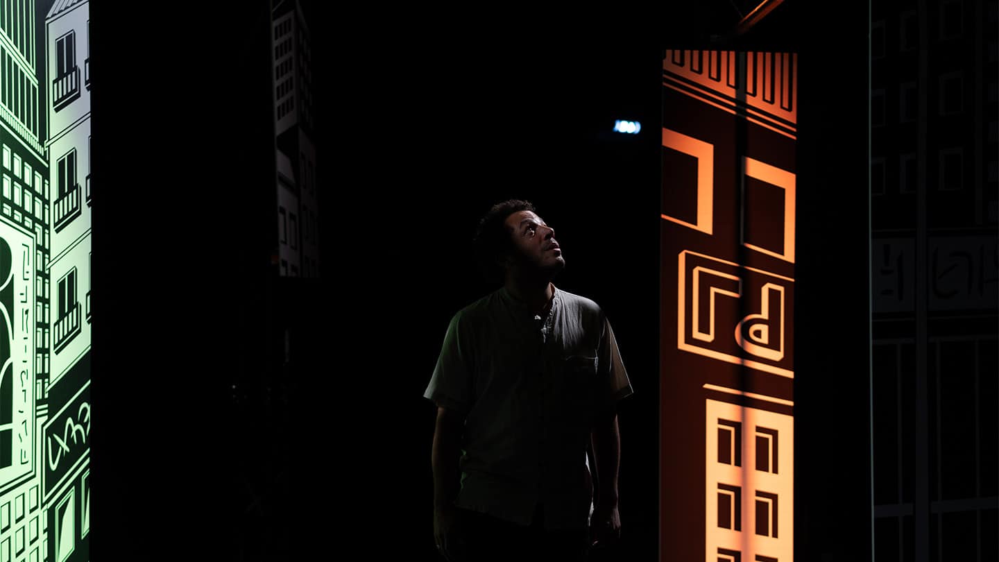 Dans un décor de grande ville, aux allures cartoonesque, un garçon regarde le ciel.