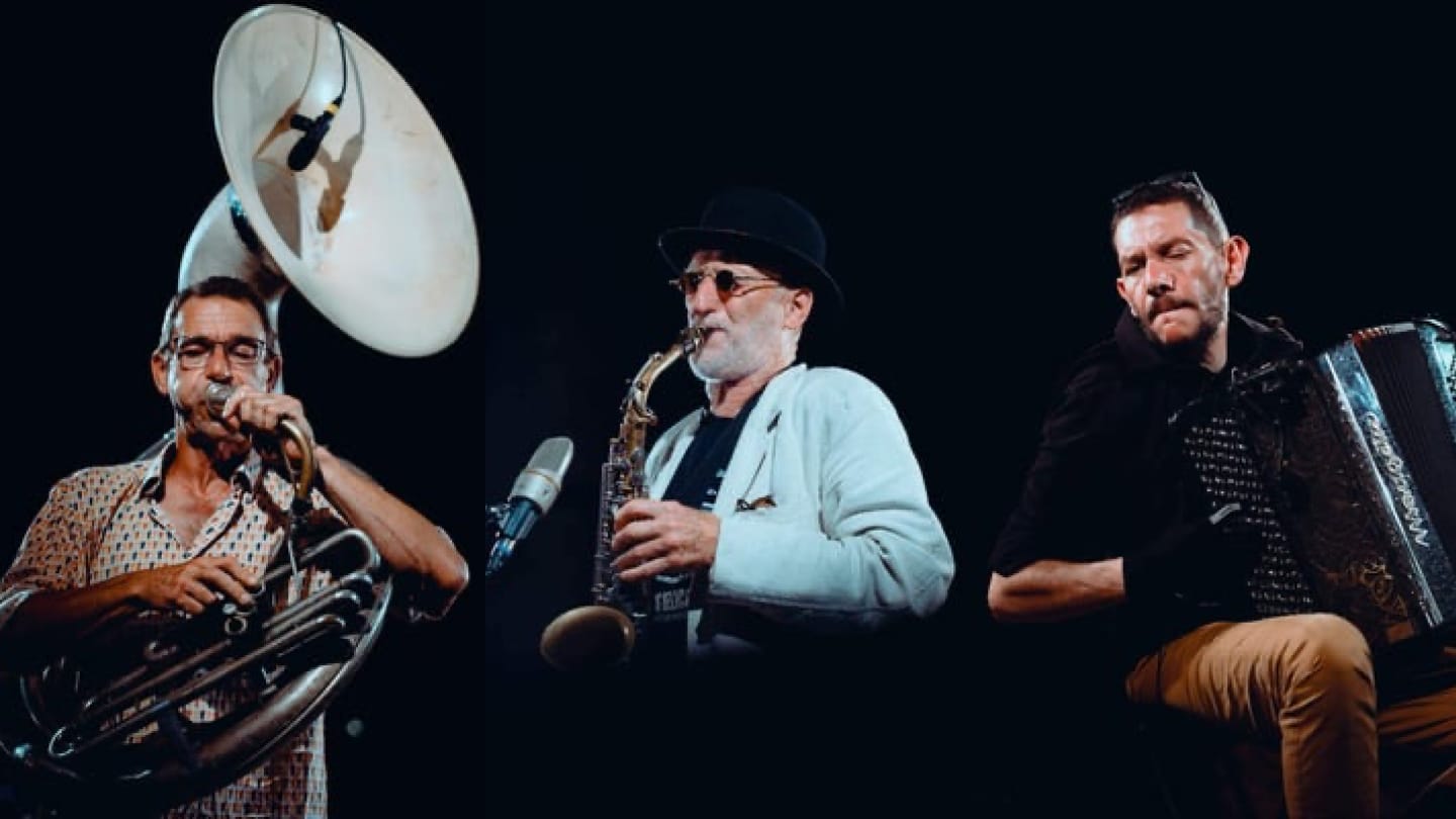 3 membres du groupe. Un avec un tuba, un avec un saxophone et un autre avec un accordéon.