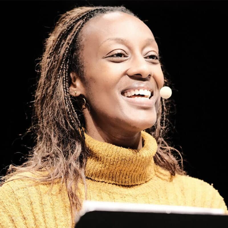 Une femme parle, la tête droite avec un grand sourire.