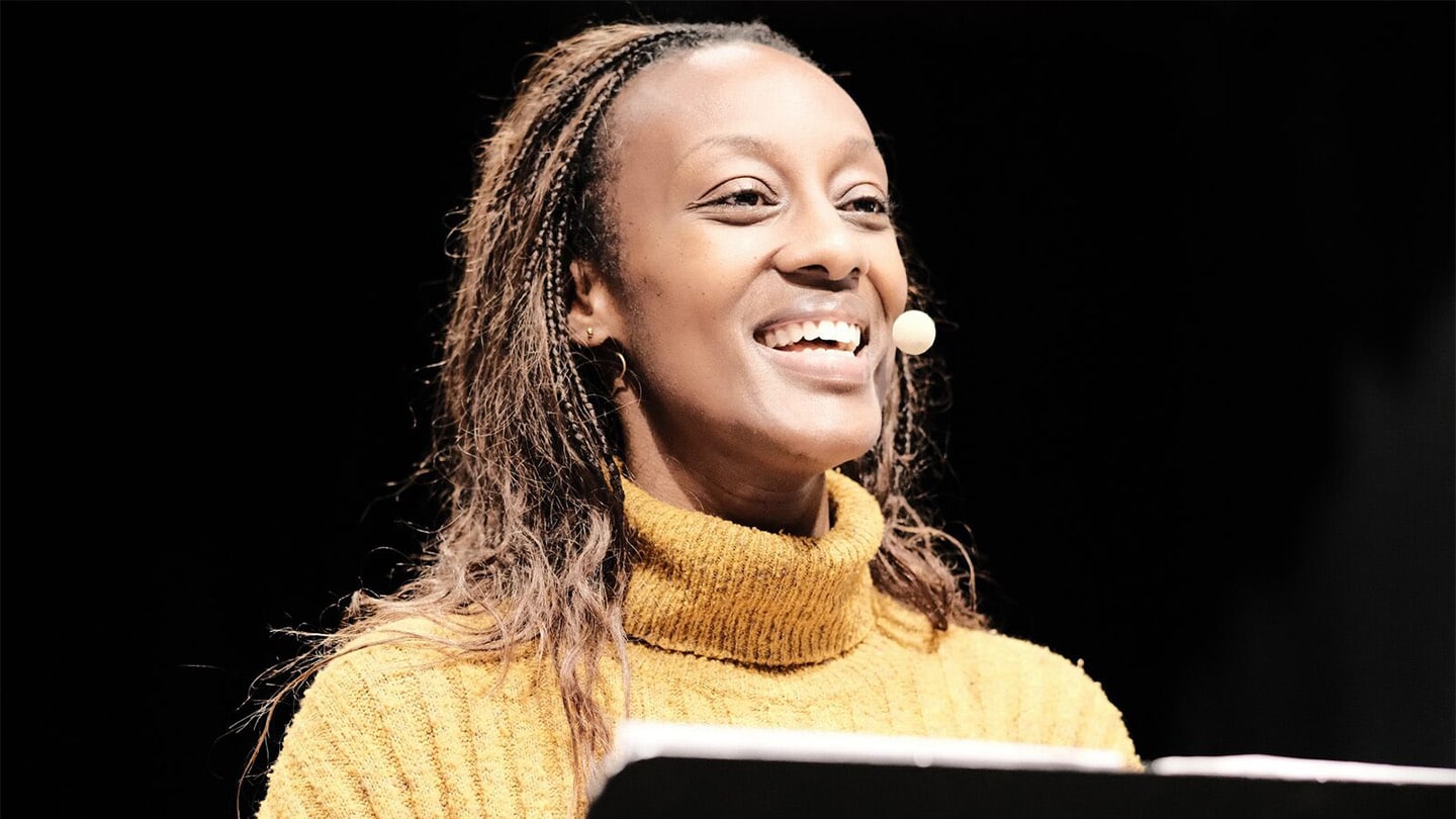 Une femme parle, la tête droite avec un grand sourire.