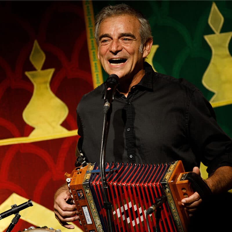 Luigi Rignanese, conteur et musicien, chante un accordéon rouge à la main.