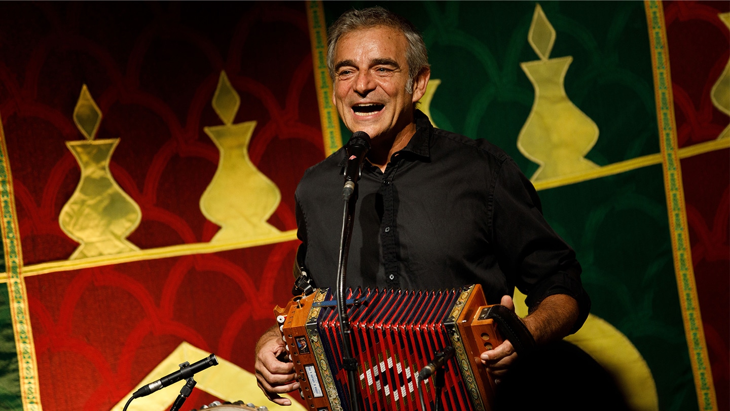 Luigi Rignanese, conteur et musicien, chante un accordéon rouge à la main.