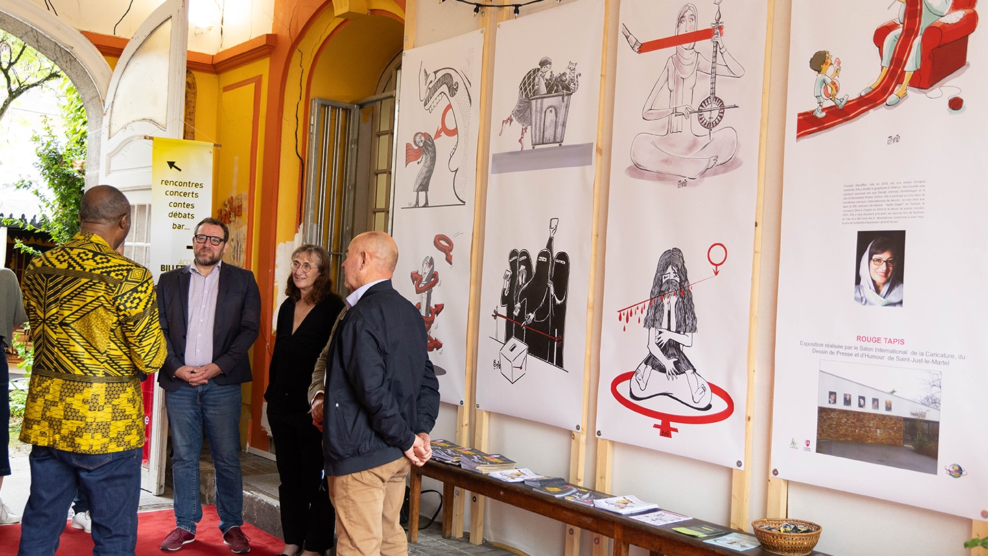 Photo du vernissage de l'exposition Rouge Tapis. 4 personnes discutent devant les dessins de Firoozeh Mozaffari que l'on aperçoit. On se trouve à l'entrée de la Maison des Francophonies.