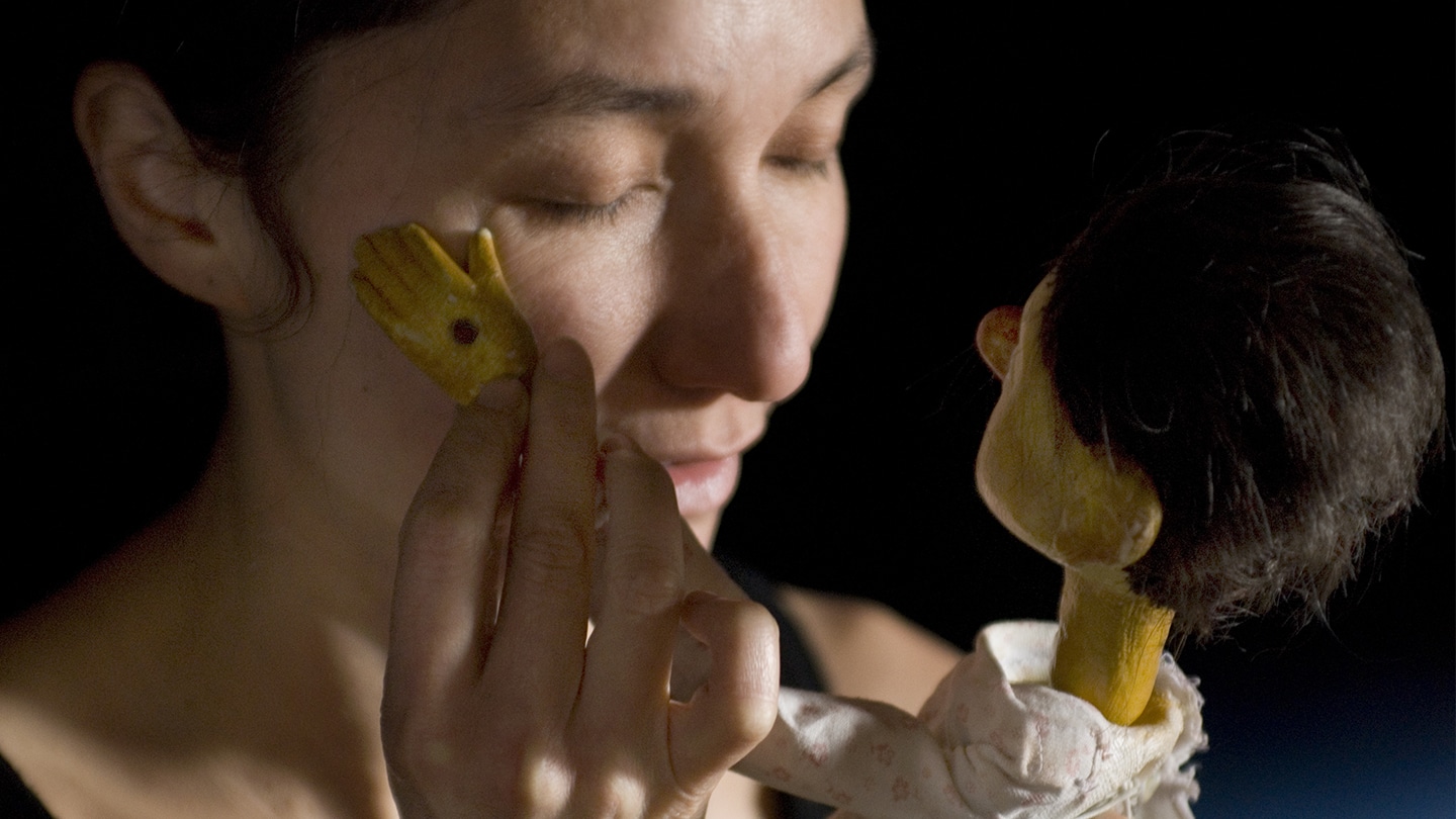 Une marionnette caresse la joue d'une femme. Elles se ressemblent.