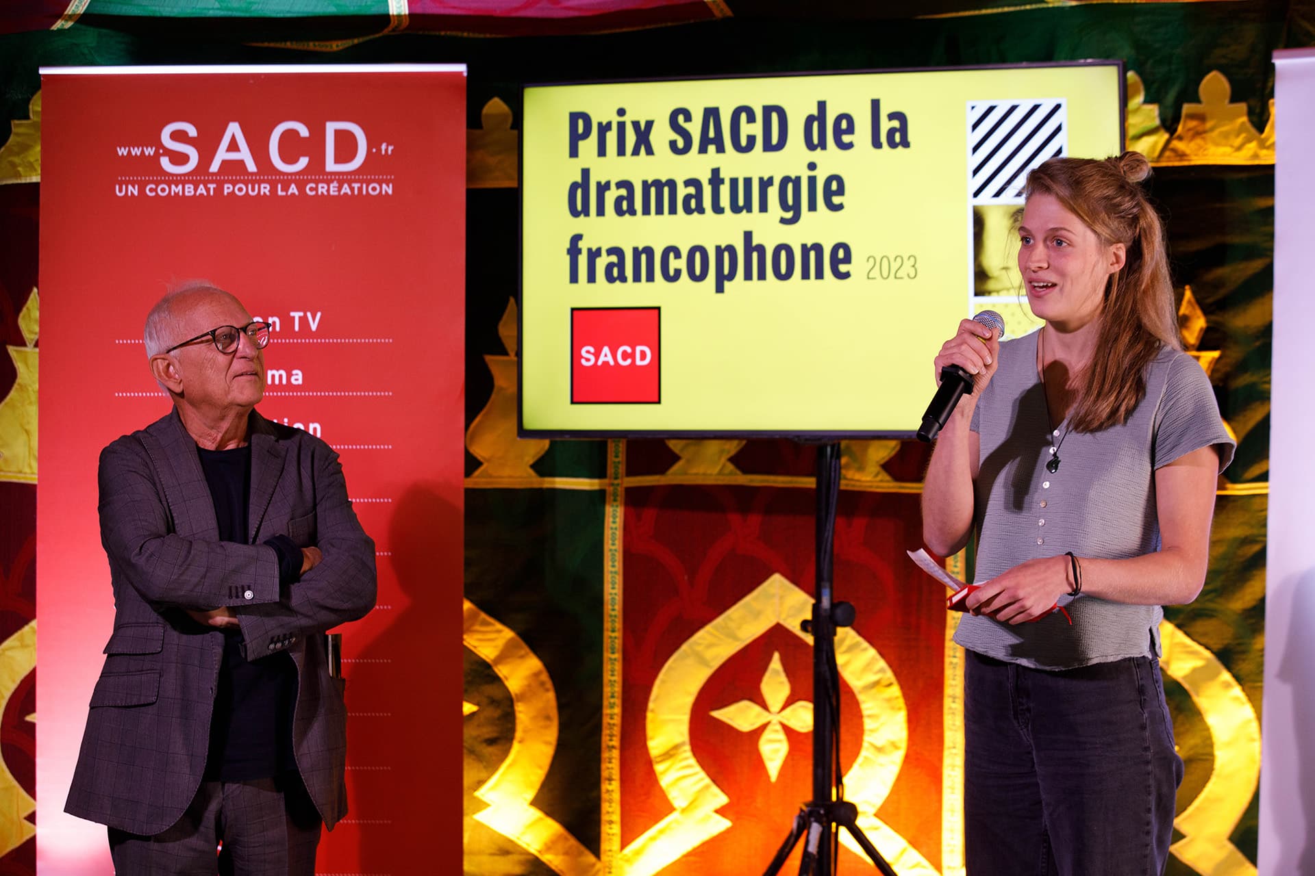 Photo de la remise du Prix SACD de la dramaturgie francophone 2023. À droite Pamela Ghislain, lauréate du prix parle. À gauche, l'homme qui lui a remis le Prix l'écoute en la regardant.