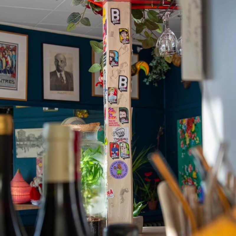 Photo de l'intérieur du bar restaurant où on voit des bouteilles de vins, des autocollants de la radio Beaubfm, des tableaux dans la décoration