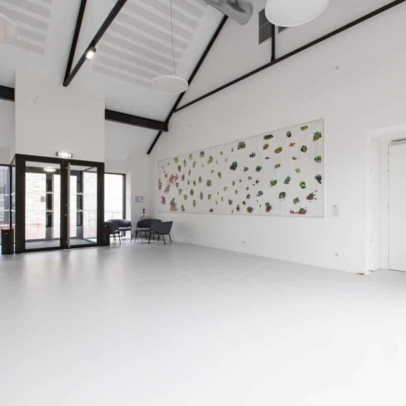 Photo du hall d'entrée de l'auditorium Sophie Dessus avec des œuvres peintes au mur et quelques fauteuils à l'entrée
