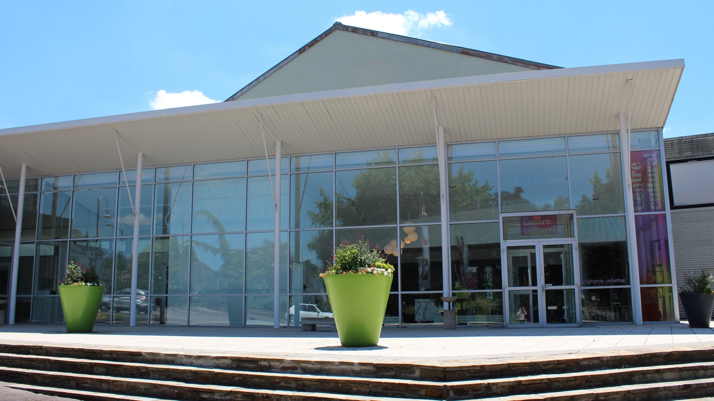 Photo du parvis du centre culturel Jean-Pierre Fabrègue , sous le soleil avec deux pots de fleurs de taille humaine