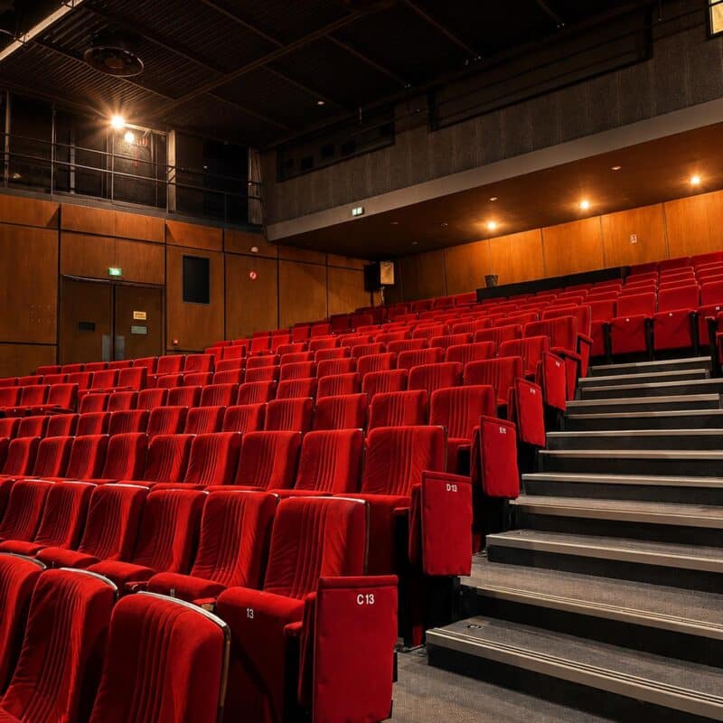 Photo de l'intérieur du théâtre depuis le bas de la salle en direction des gradins de siège avec des murs en panneaux de bois et un balcon