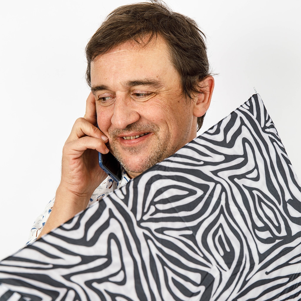 Portrait d'Alban Coulaud au téléphone avec un parapluie zèbre devant lui?