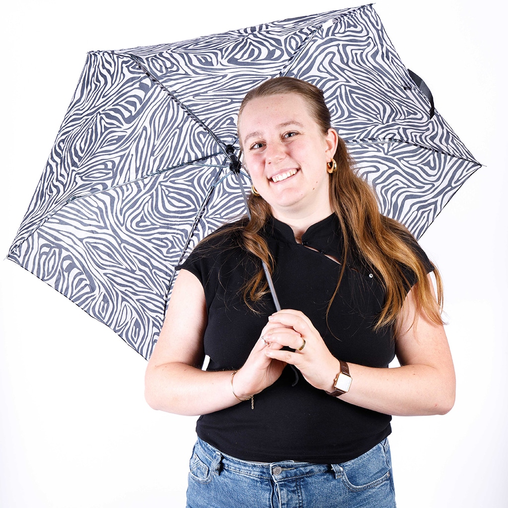 Portrait de Justine Dassier, un parapluie zébré au dessus de sa tête
