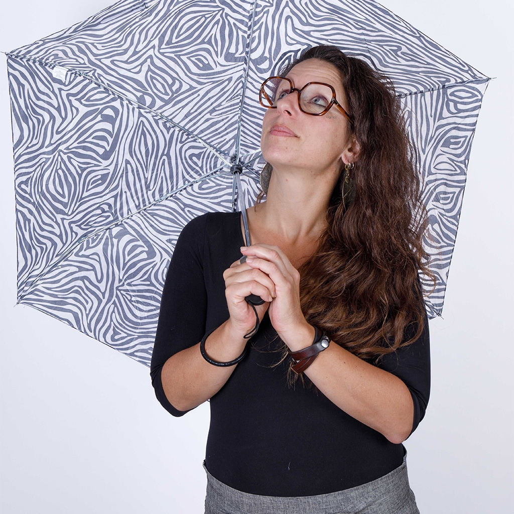 Portrait de Laure Rudler. Elle tien un parapluie zébré et regarde en l'air.