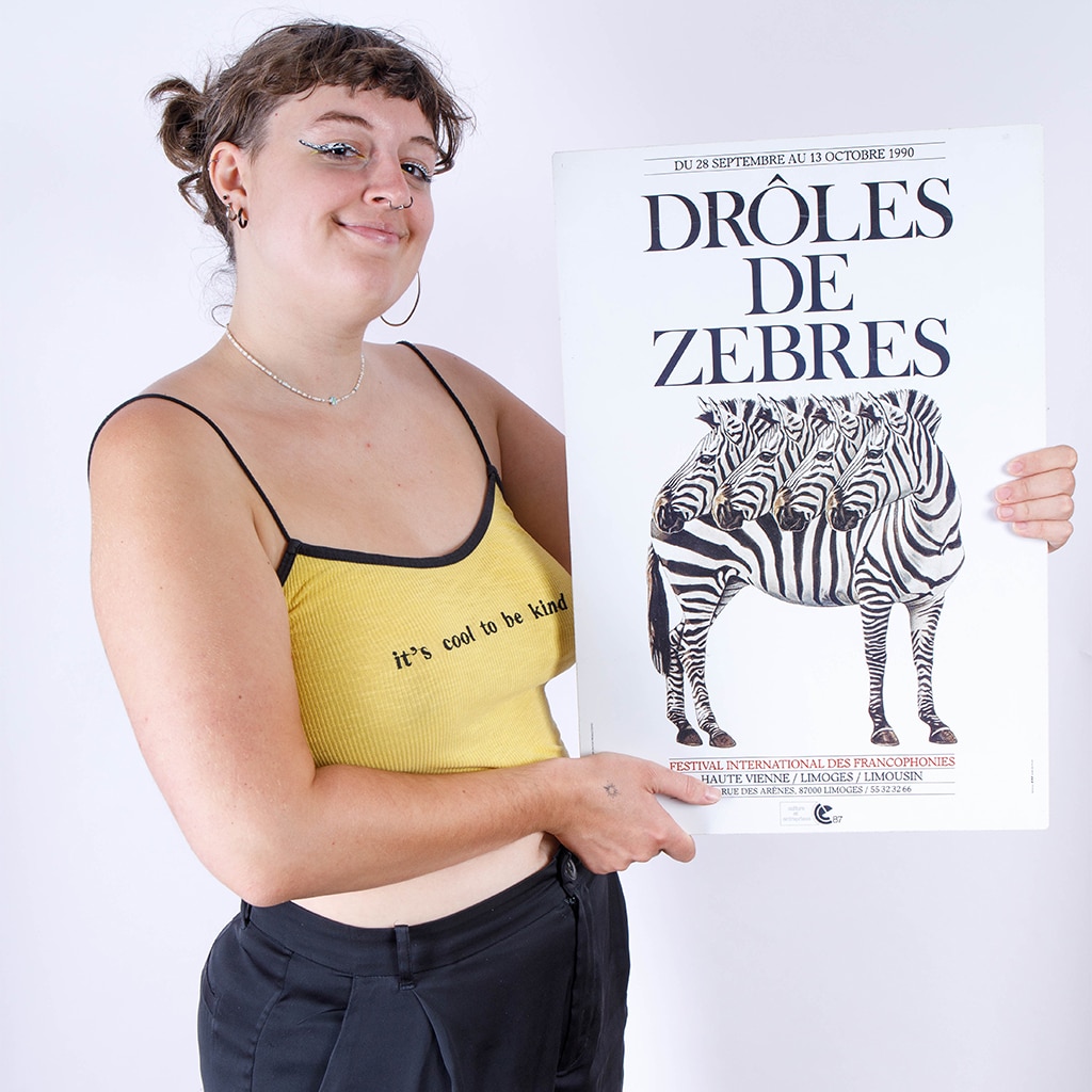 Portrait de Maud Egrot tenant dans ses mains une affiche où il est inscrit 